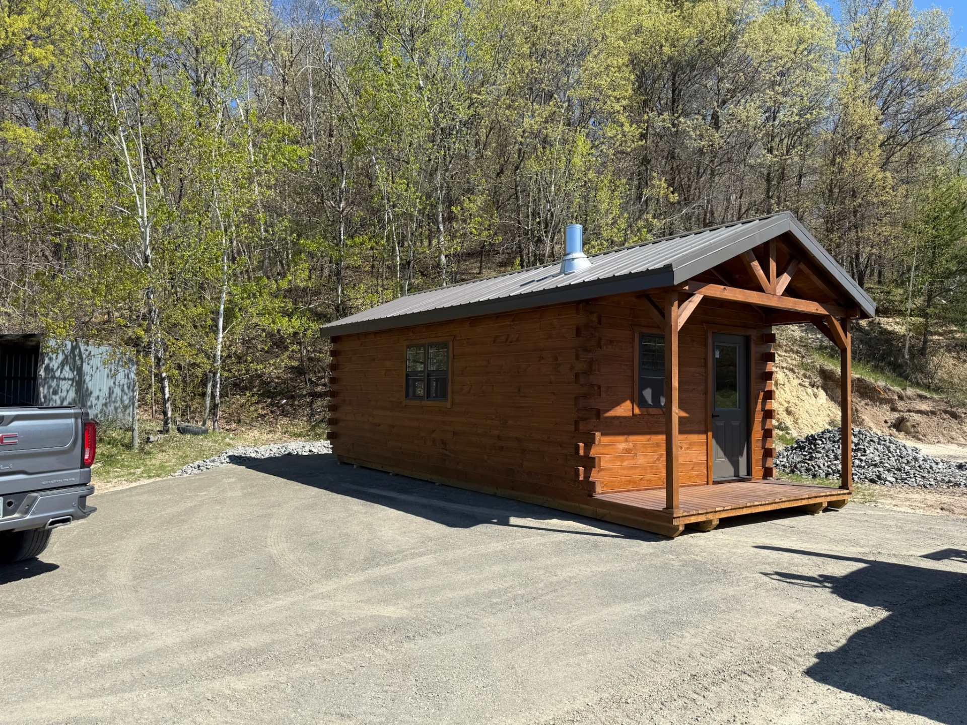 Finished stained log cabin with covered porch and steel roof