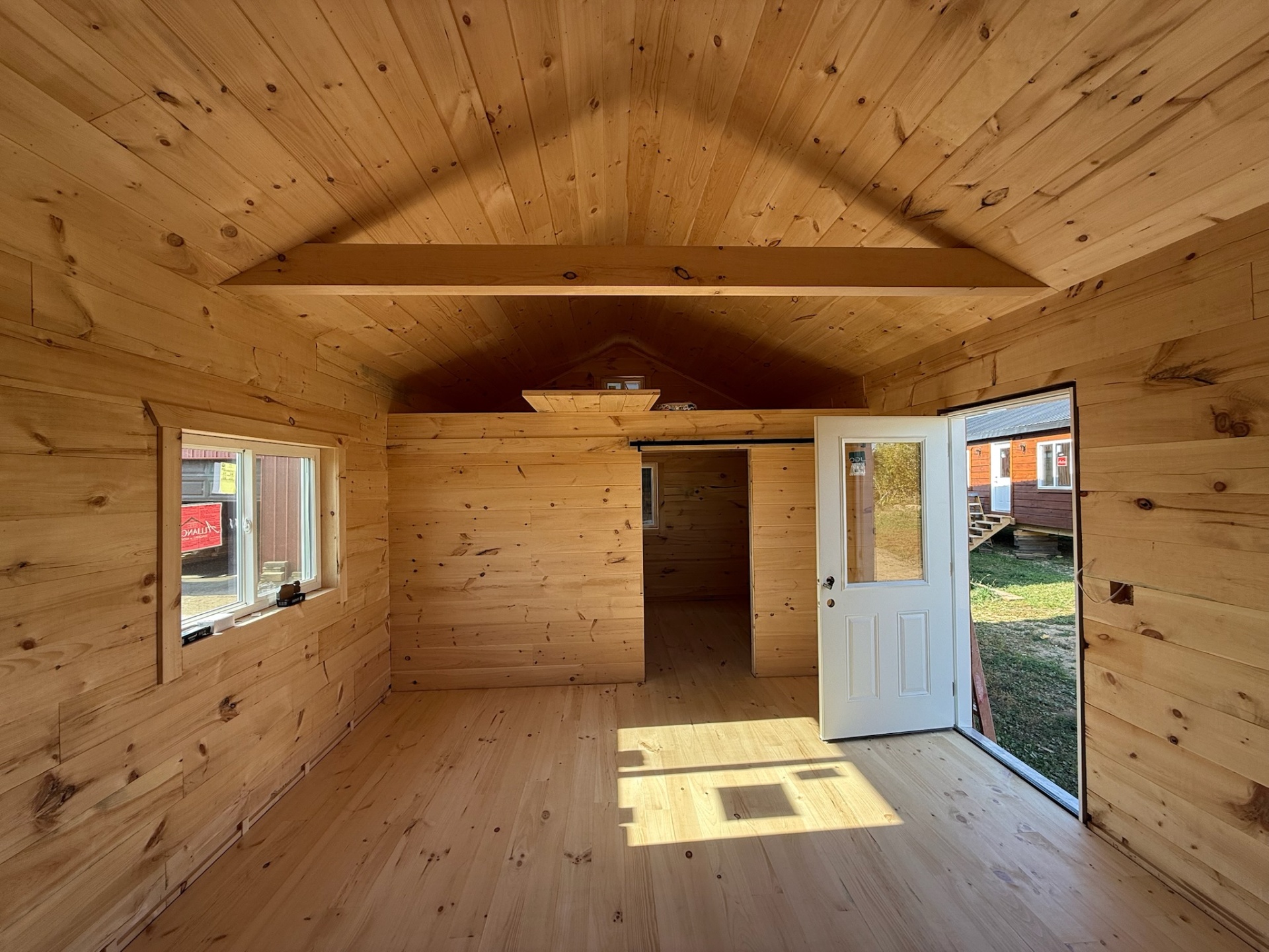 Cabin main room looking out the front door with sleeping loft above