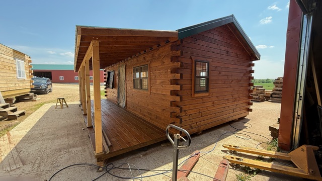 Stained log cabin with covered porch mid-build
